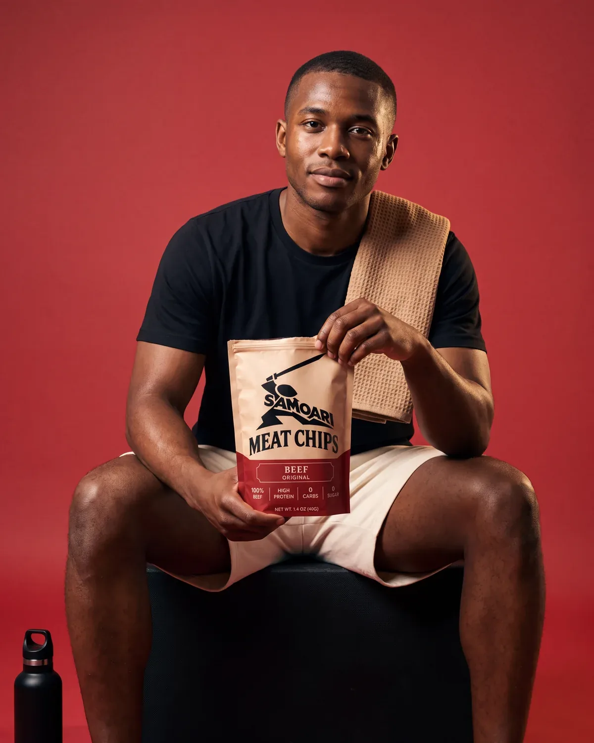 A man resting after training holding a bag of Samoari Meat Chips, Beef Original